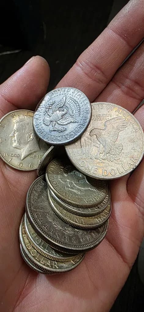 A hand holding silver half dollars and Eisenhower dollars at the Don Pepes counter